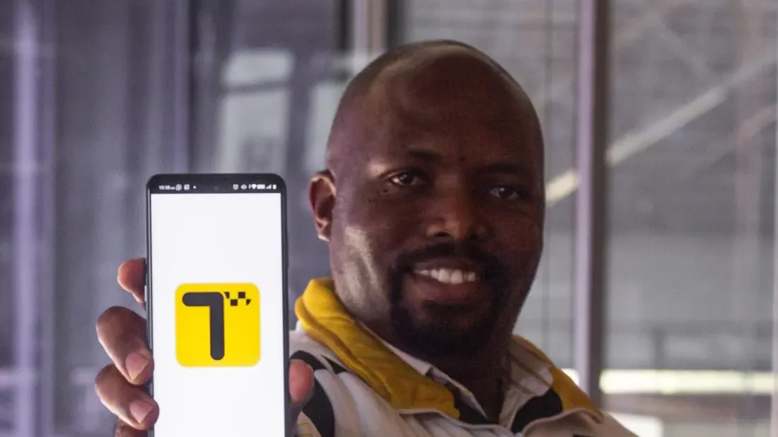 A happy Teksi Ride team member holding up the Teksi app